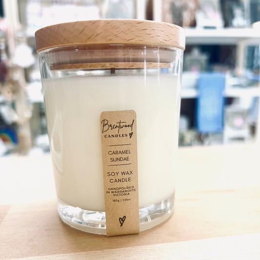 Caramel Sundae Scented candle in a clear glass container and a light natural timber lid. Sitting on timber shop counter in Warrandyte.