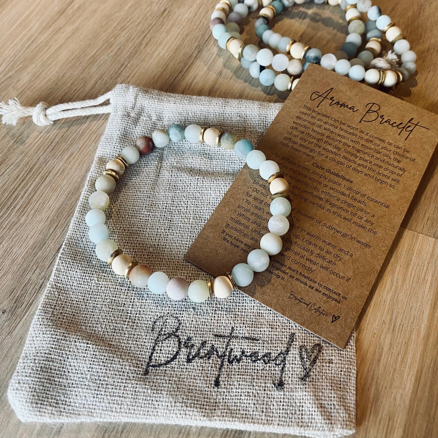 Amazonite aroma bracelet/diffuser bracelet made from 6mm amazonite & natural white wood beads with brass heishi disc embellishments. Laid on cloth pouch/drawstring bag stamped with “Brentwood” and an aroma bracelet information and care card on kraft brown card. 